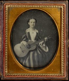 an old photo of a woman with a guitar in her lap and wearing a striped dress