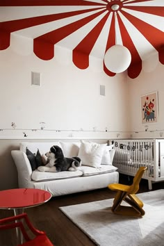 a living room with a white couch, red and white striped ceiling and wooden floors