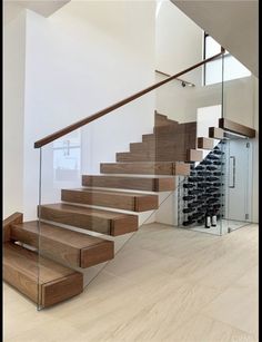 there is a glass stair case next to the wine rack in this room with wood floors