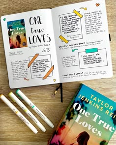 an open book sitting on top of a wooden table next to some markers and pencils