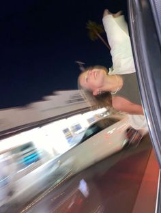 a woman standing in the back of a car at night