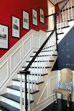 there is a black and white stair case next to the wall with pictures on it