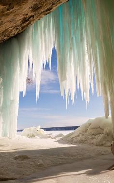 an ice cave with icicles hanging from it's ceiling and water in the background