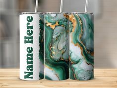 two green and gold marbled tumbles on a wooden table