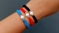 three different colored bracelets with pearls and beads on the wrist, one in red, one in blue