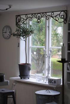 a potted plant sitting on top of a window sill next to a clock