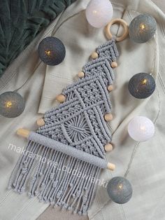 a knitted christmas tree ornament surrounded by balls and lights on a blanket