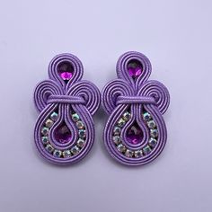 pair of purple earrings with crystal stones on white background