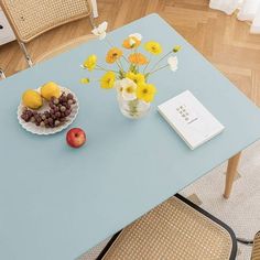 a blue table topped with fruit and flowers on top of a hard wood floored floor