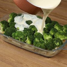 broccoli is being poured into a casserole dish with ranch in the background