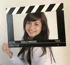 a woman holding up a black and white movie clapper frame with the words screen director on it