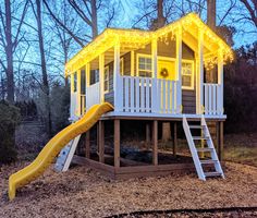 a small house with a yellow slide and lights on the roof is lit up at night