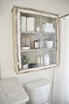 a white toilet sitting in a bathroom next to a window filled with towels and other items