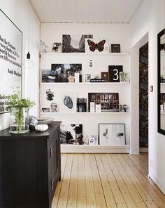 a living room filled with lots of books and pictures on the wall next to a wooden floor