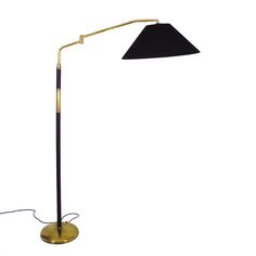 a floor lamp with a black shade on it's side and a cord attached to the base