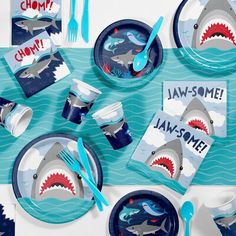 a table set up with shark plates and napkins