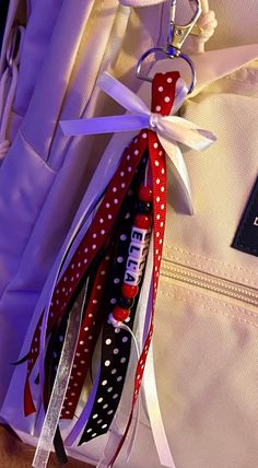 a white suitcase with red, black and white ribbons attached to it