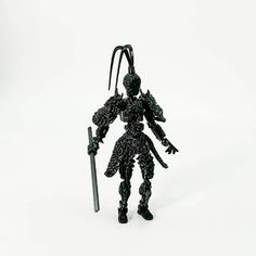 an action figure holding a knife and wearing a black outfit on a white background with no one around it