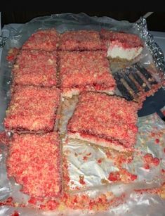 there is a cake that has been cut into squares and placed on tin foil with a spatula