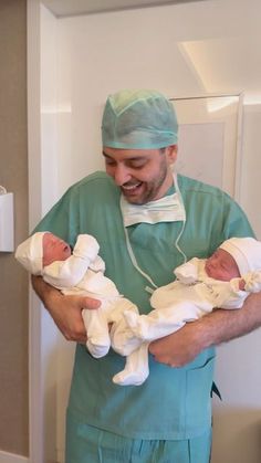 a man in scrubs holding two babies