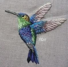 a colorful hummingbird sitting on top of a piece of cloth