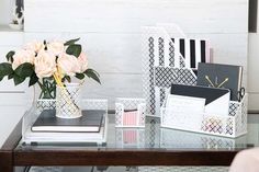 there is a vase with flowers and cards on the table in front of it, along with other office supplies