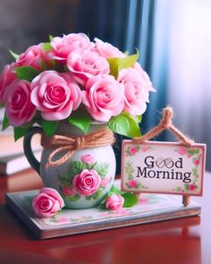 pink roses are in a vase next to a sign that says good morning on it