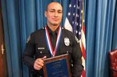 a man in uniform holding an award while standing next to a flag and blue curtain