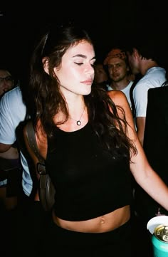 a woman standing in front of a group of people at a party with her eyes closed