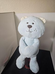 a stuffed bear sitting on top of a black table next to a white wall and door