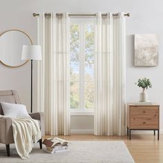 a living room with a couch, chair and large window covered in white drapes