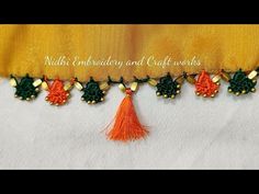 an orange and green tassel hanging from the side of a yellow curtain with gold trim