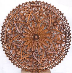 an intricately carved wooden wall hanging on a white wall