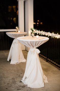 two white tables with bows and candles on them