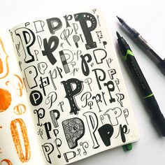 an open notebook with black and orange doodles on it, next to two markers