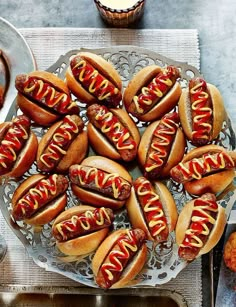 hotdogs with ketchup and mustard are on a platter next to other food items