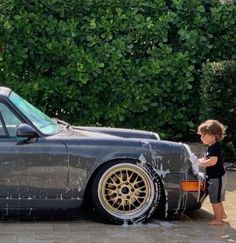 a young boy washing his car in the driveway