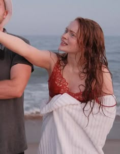 a man standing next to a woman on top of a beach