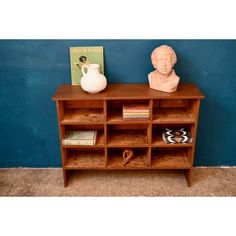 a wooden shelf with books and a vase on it next to a blue painted wall