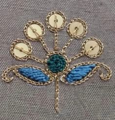 a blue and gold brooch sitting on top of a gray fabric covered table cloth