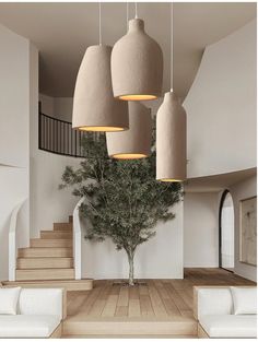 a living room filled with lots of white furniture and hanging lights over the couches