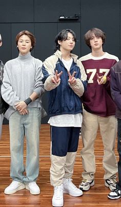 four young men standing in front of a basketball court with their hands up to the side