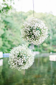 two hanging white balls filled with baby's breath flowers are suspended from the ceiling