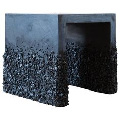 an artistic sculpture made out of concrete blocks and rocks on the outside, with one section partially covered in black rock