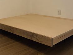 an empty bed frame in a room with hard wood flooring and white paint on the walls