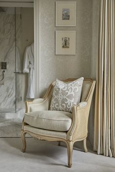 a white chair sitting in front of a shower next to a wall with pictures on it