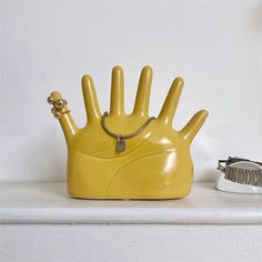 a yellow hand shaped object sitting on top of a white shelf next to a dog collar