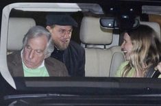 an older man and woman sitting in the back seat of a car talking to each other