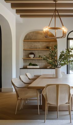 a dining room table with chairs and a potted plant