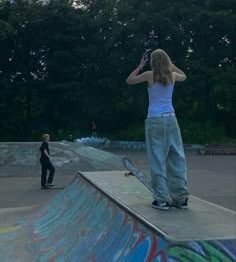 a person on a skateboard is at the top of a ramp with another person in the background